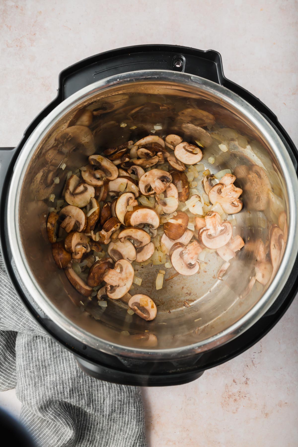 An overhead view of sautéed onions and mushrooms in an Instant Pot.