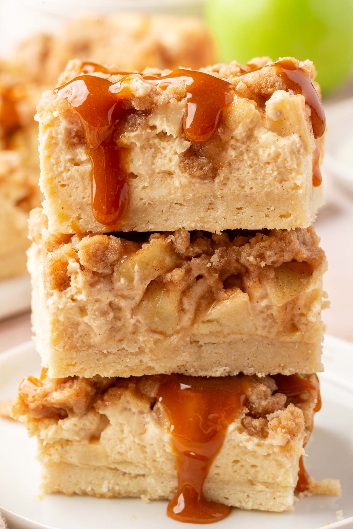A stack of three gluten free caramel apple cheesecake bars on a dessert plate.
