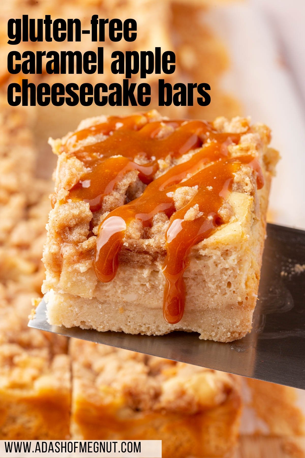 A metal spatula lifting a gluten-free cheesecake bar with apples and cinnamon streusel from a large pan.