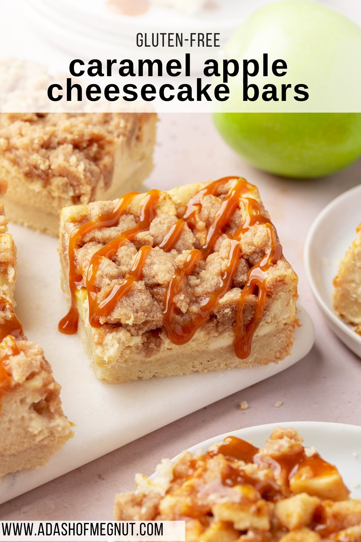 A gluten free cheesecake bar with apples, streusel and caramel drizzle on a platter with additional gluten free bars scattered around.