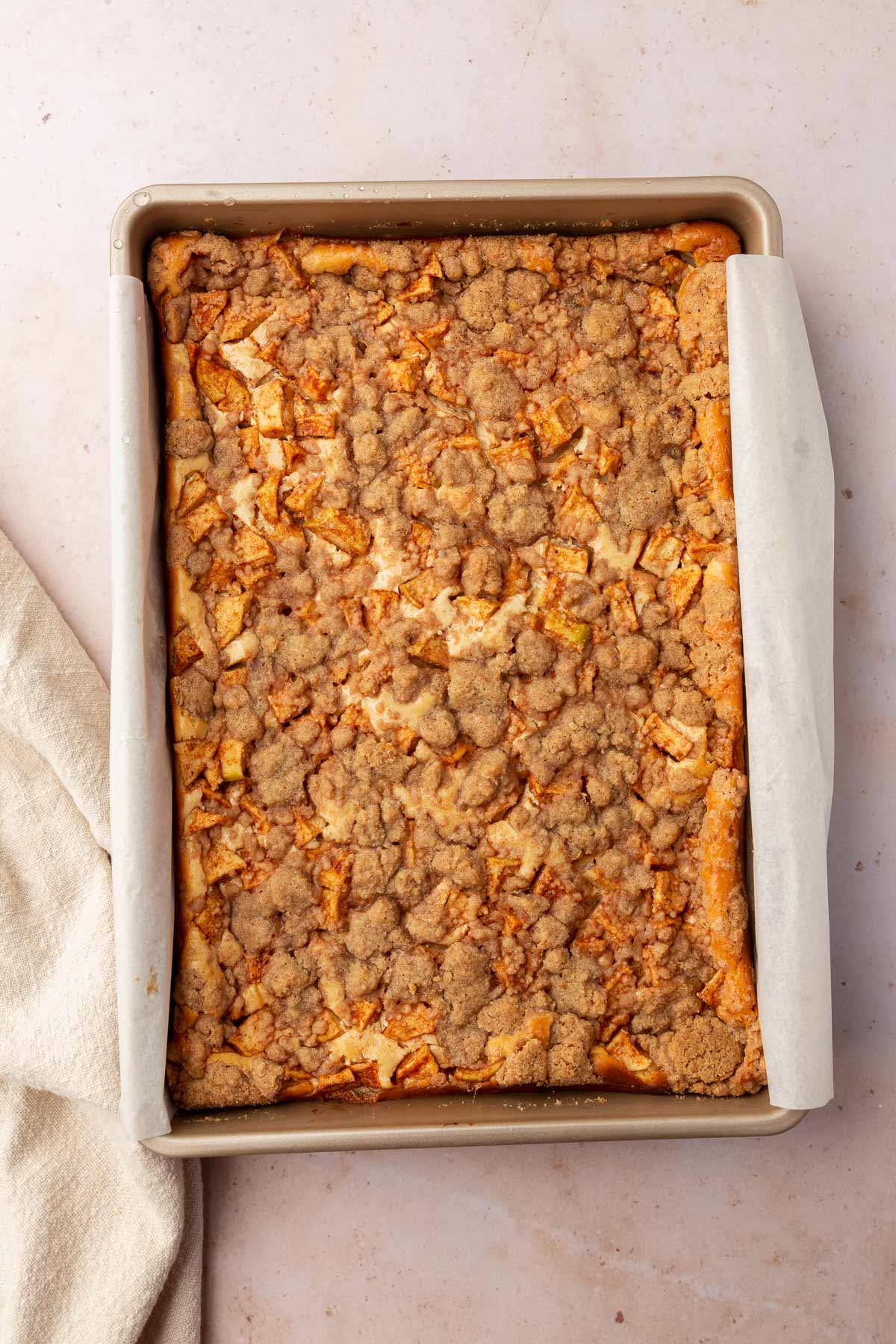 An overhead view of a rectangle baking pan filled with gluten-free apple cheesecake bars with streusel after coming out of the oven.