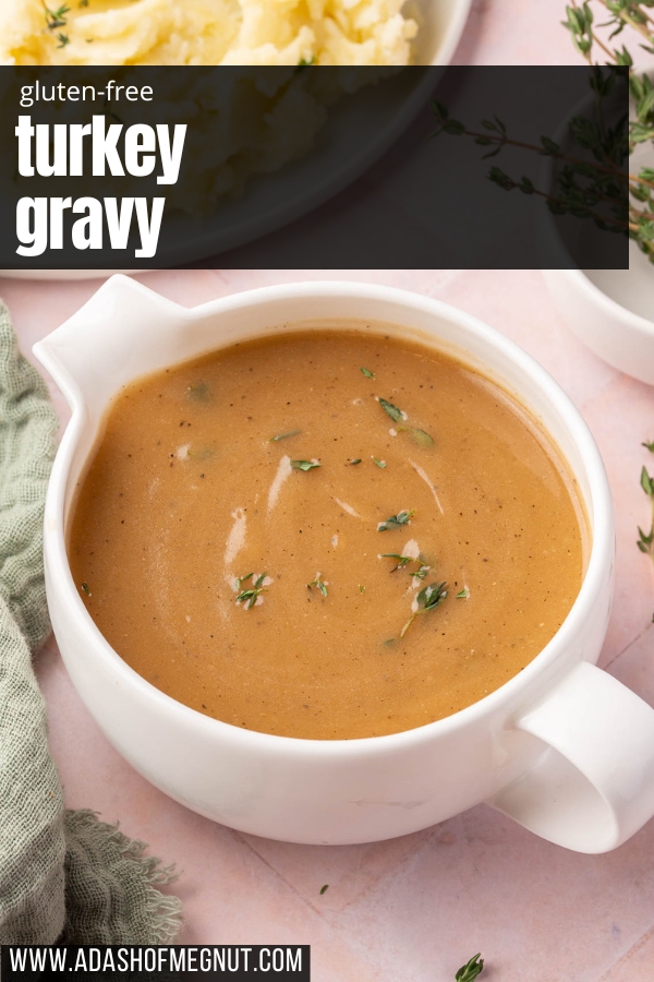 A round gravy boat filled with gluten-free gravy topped with fresh thyme with a serving of mashed potatoes in the corner.