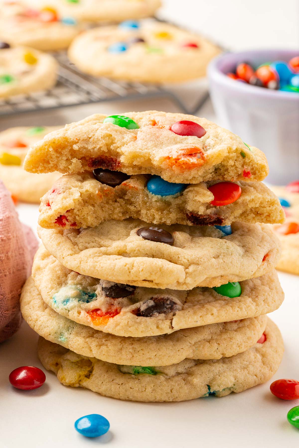 A stack of six gluten-free M&M cookies with the top to ripped in half to show the insides.