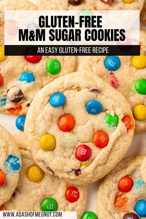 A close up of gluten free M&M sugar cookies overlapping over each other.