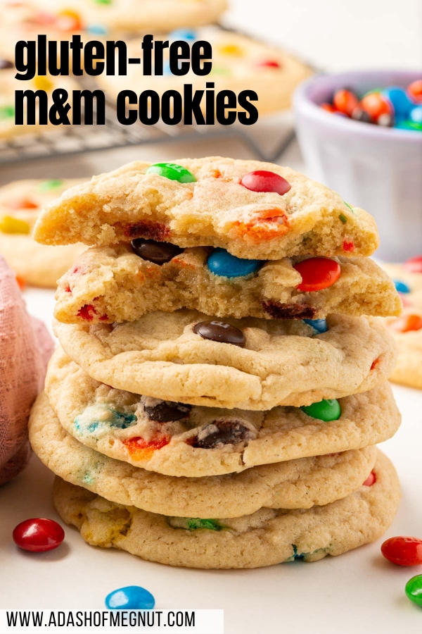 A stack of six gluten free M&M sugar cookies with the top two broken in half to see the chewy insides.
