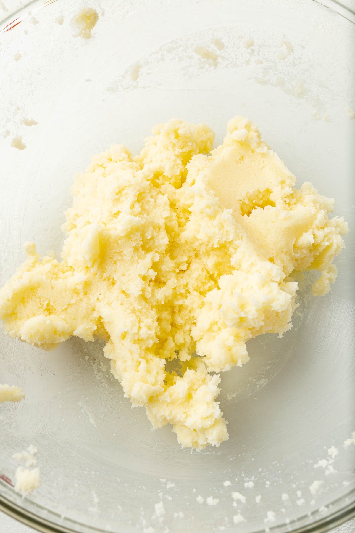 A glass mixing bowl of creamed butter and granulated sugar.