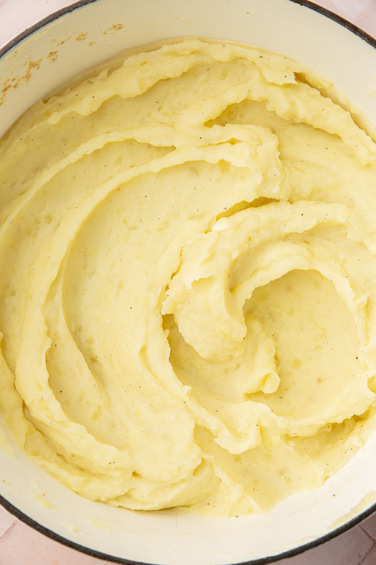 A dutch oven with creamy mashed potatoes in a swirled pattern.