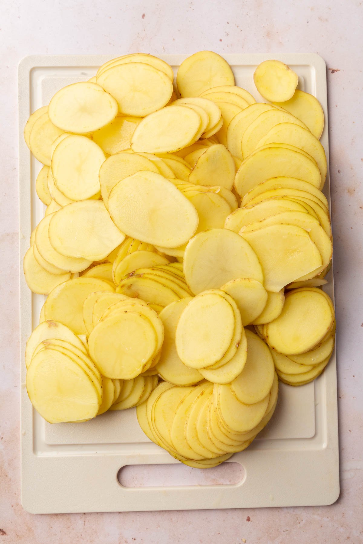 Slices of yukon gold potatoes on a cutting board.