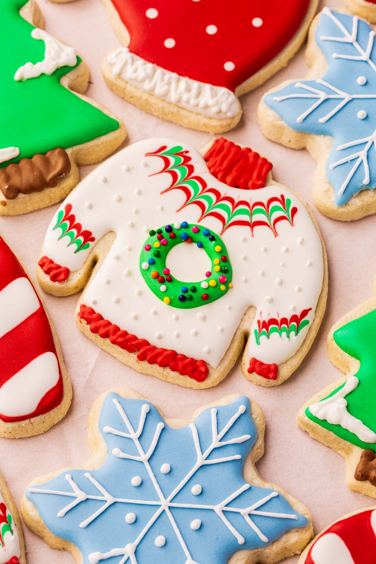 A close up of gluten-free Christmas cookies decorated as ugly Christmas sweaters, snowflakes, Christmas trees, candy canes and polka dot mittens.