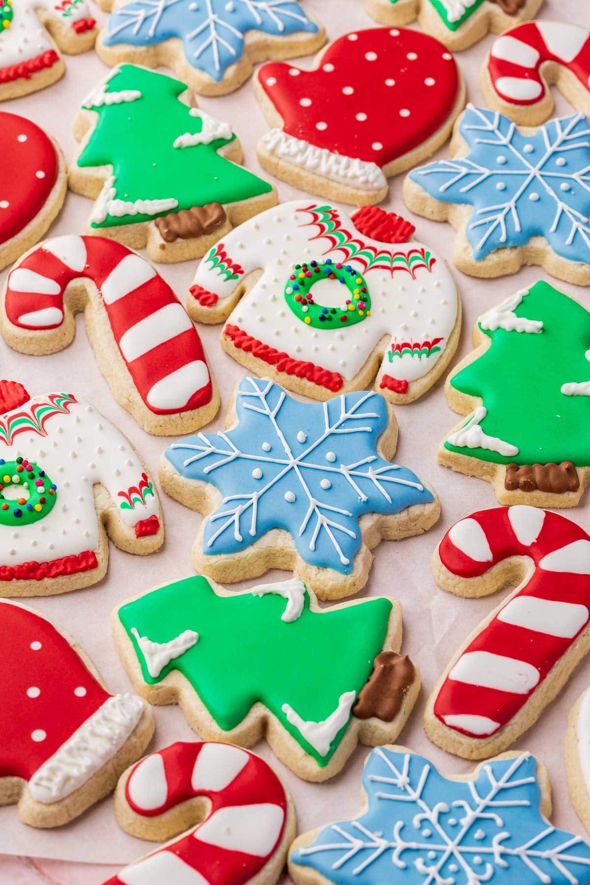 A close up of gluten-free Christmas cookies decorated with royal icing as ugly Christmas sweaters, snowflakes, Christmas trees, candy canes and polka dot mittens.