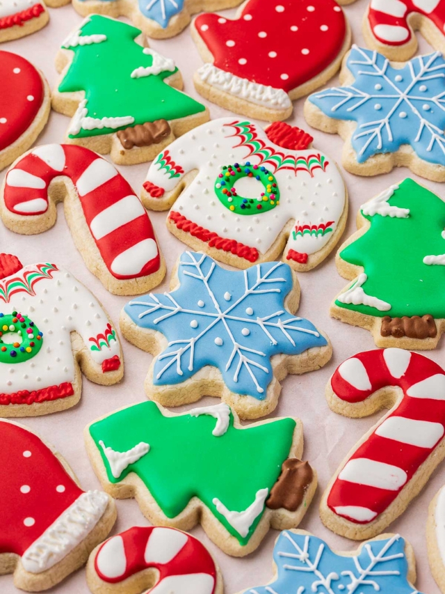 A close up of gluten free Christmas cookies decorated as ugly Christmas sweaters, snowflakes, Christmas trees, candy canes and polka dot mittens.