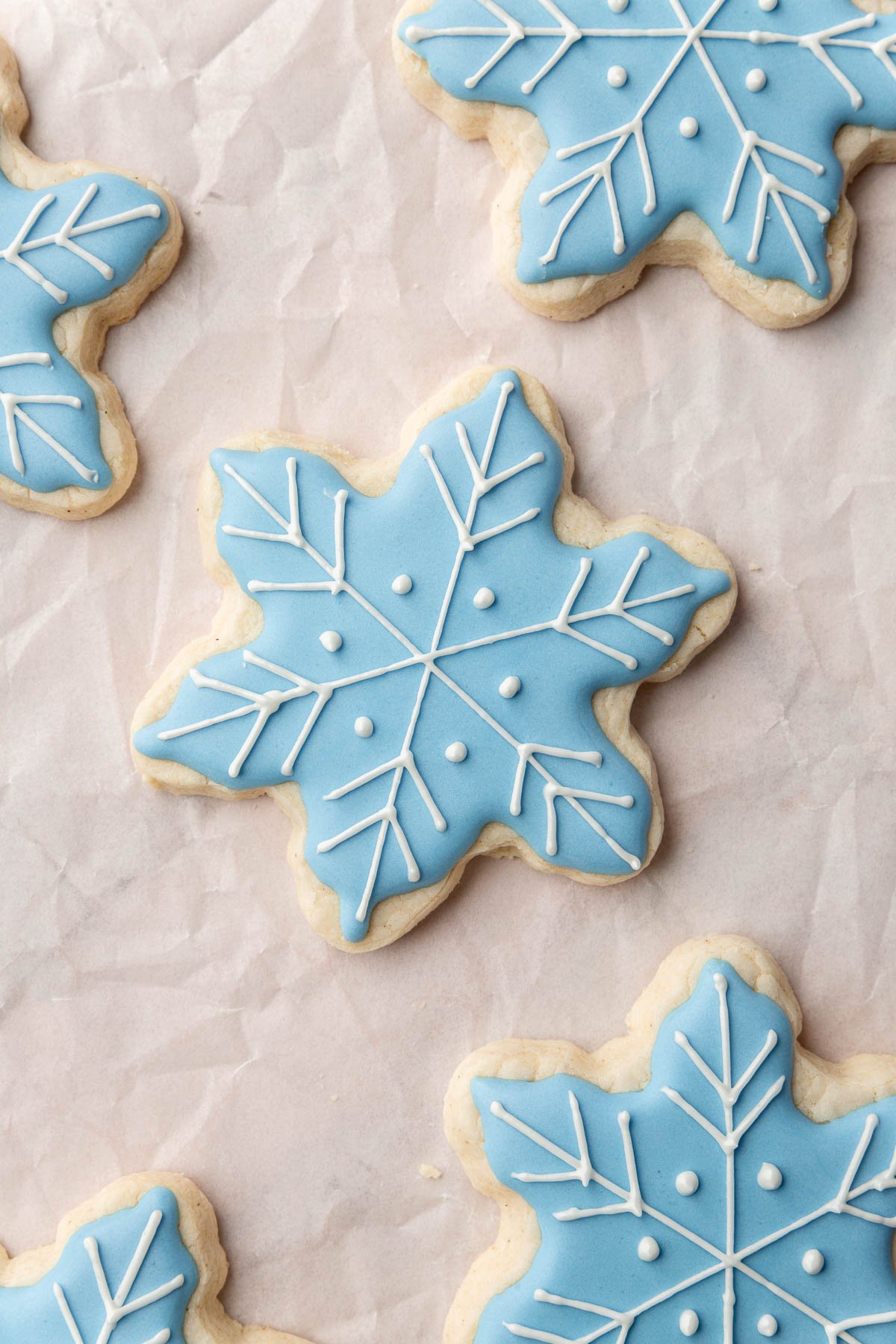 A few gluten-free snowflake sugar cookies decorated with blue royal icing and white royal icing details on top.