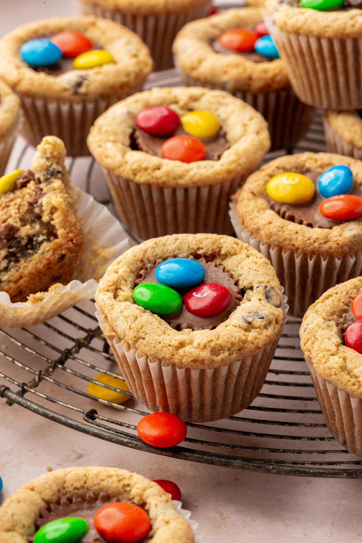 Multiple peanut butter cup cookies with M&Ms on a round wire cooling rack.