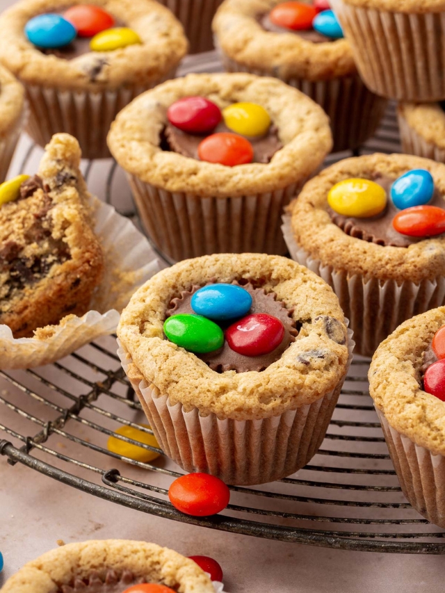 Multiple peanut butter cup cookies with M&Ms on a round wire cooling rack.