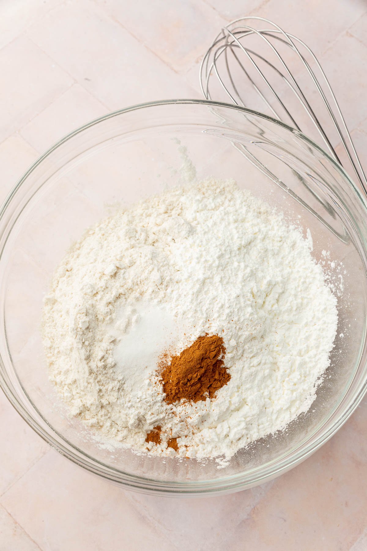 A glass mixing bowl with gluten-free flour, salt, cornstarch, and cinnamon in it before whisking together.