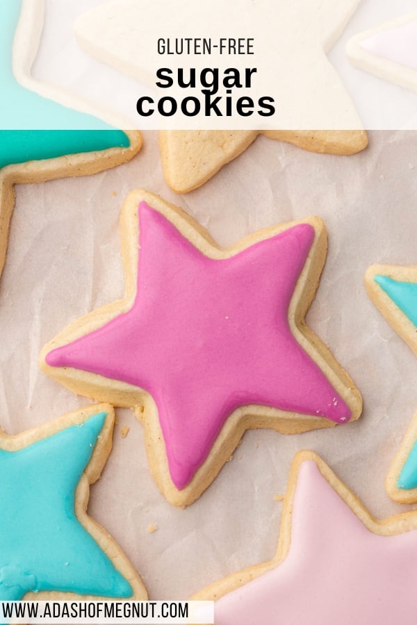 An overhead view of star sugar cookies decorated with pink, blue and light pink royal icing on a piece of parchment paper.
