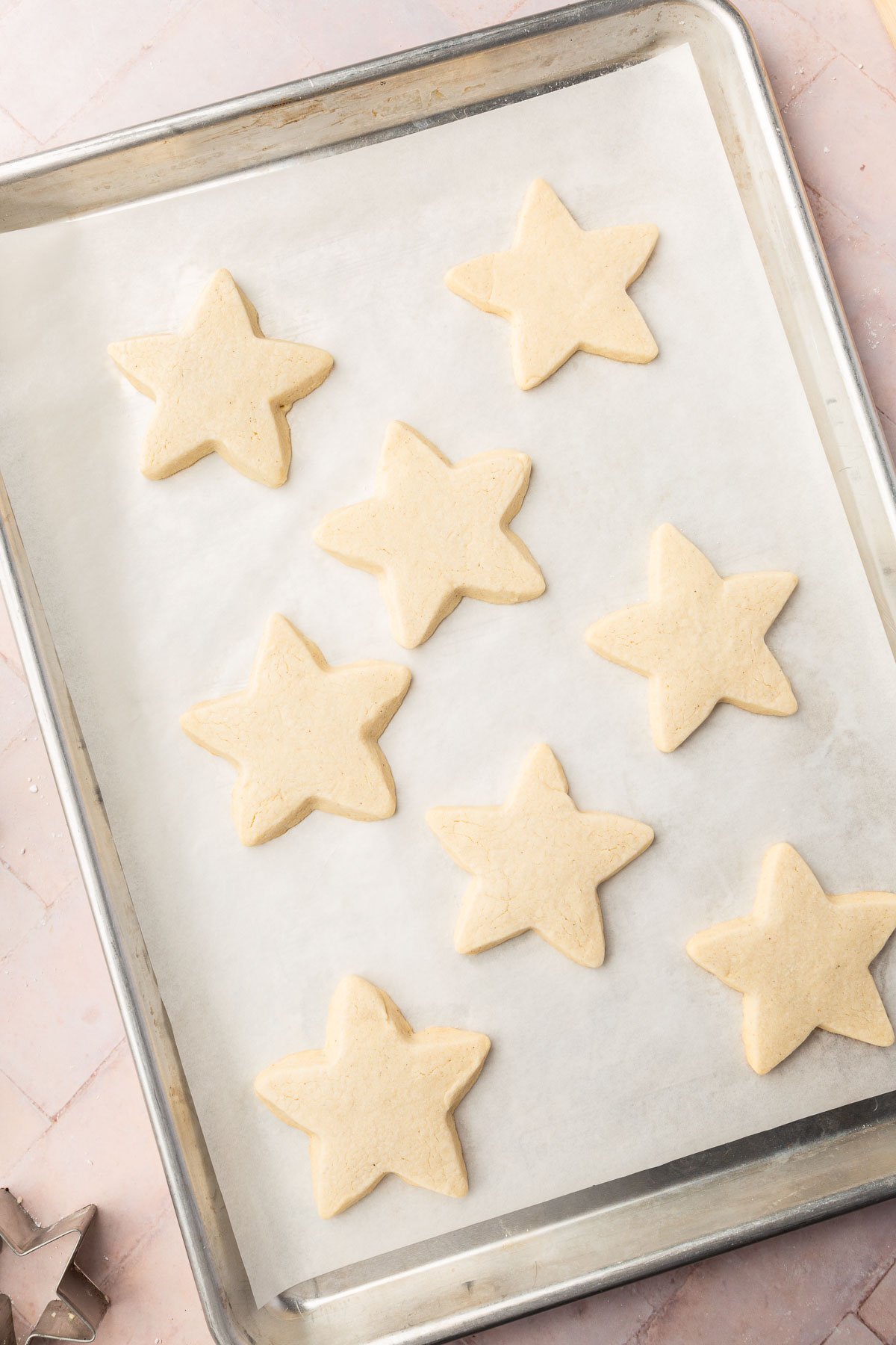 Star shaped gluten free sugar cookies on a baking sheet lined with parchment paper after baking in oven.