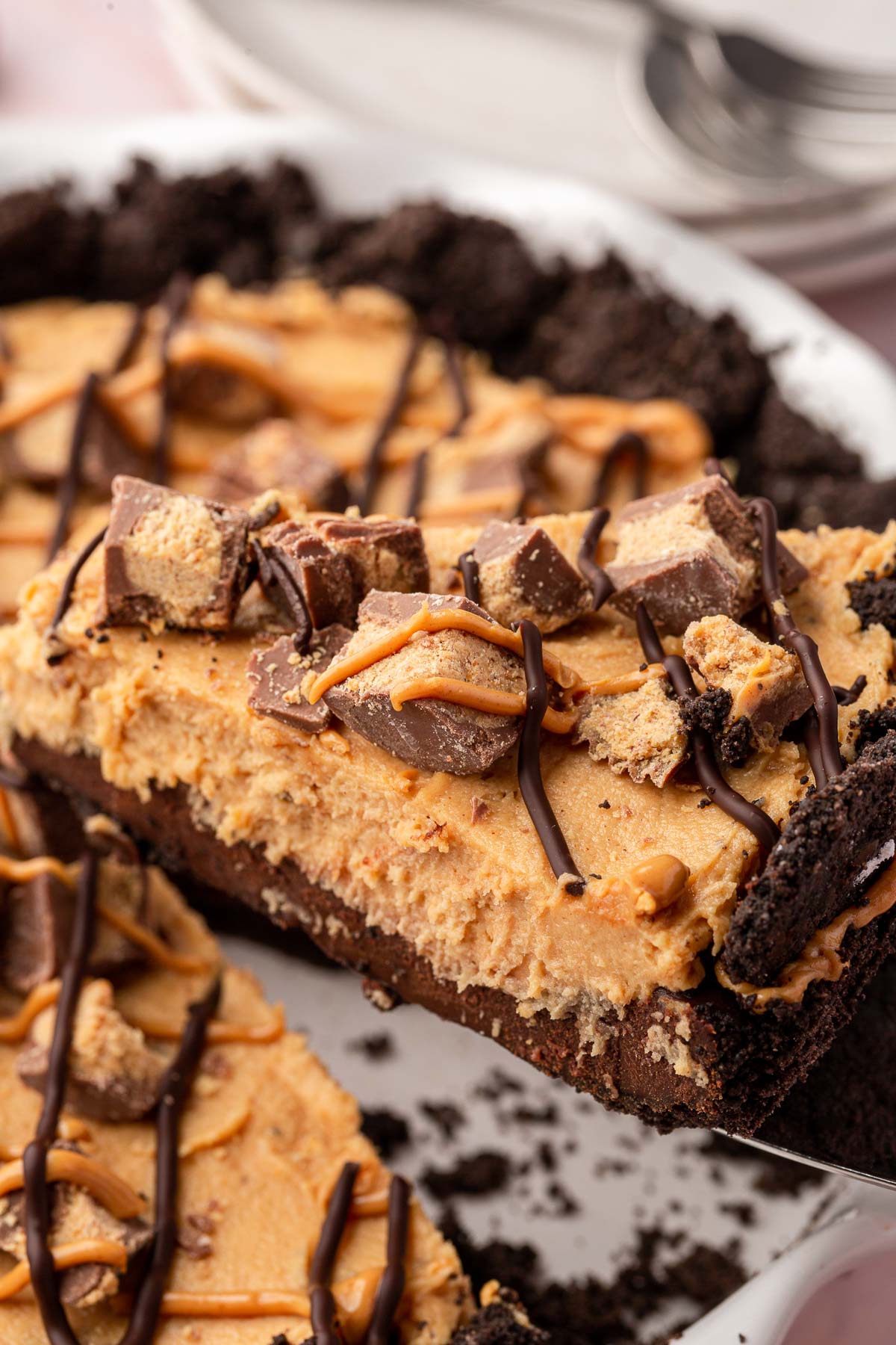 A slice of Oreo peanut butter pie being removed from the larger pie with a serving knife.