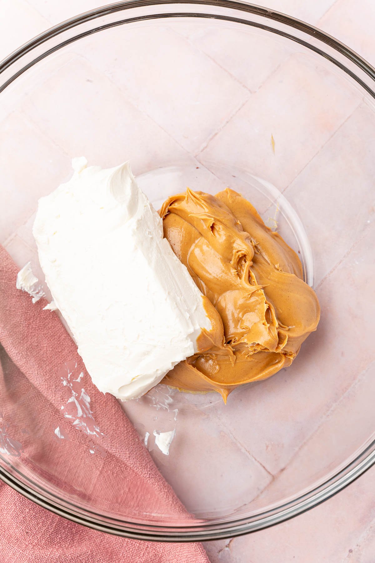 Cream cheese and peanut butter in a glass mixing bowl before mixing together.