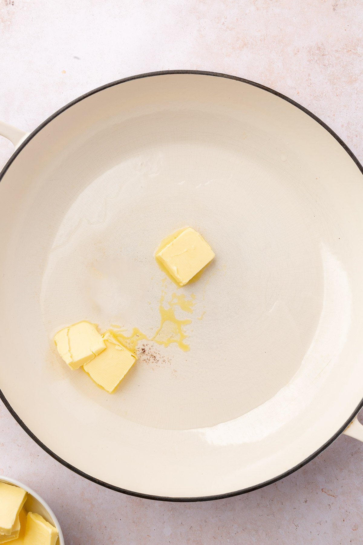 A braising pan with three tablespoons of butter in it that are starting to melt.