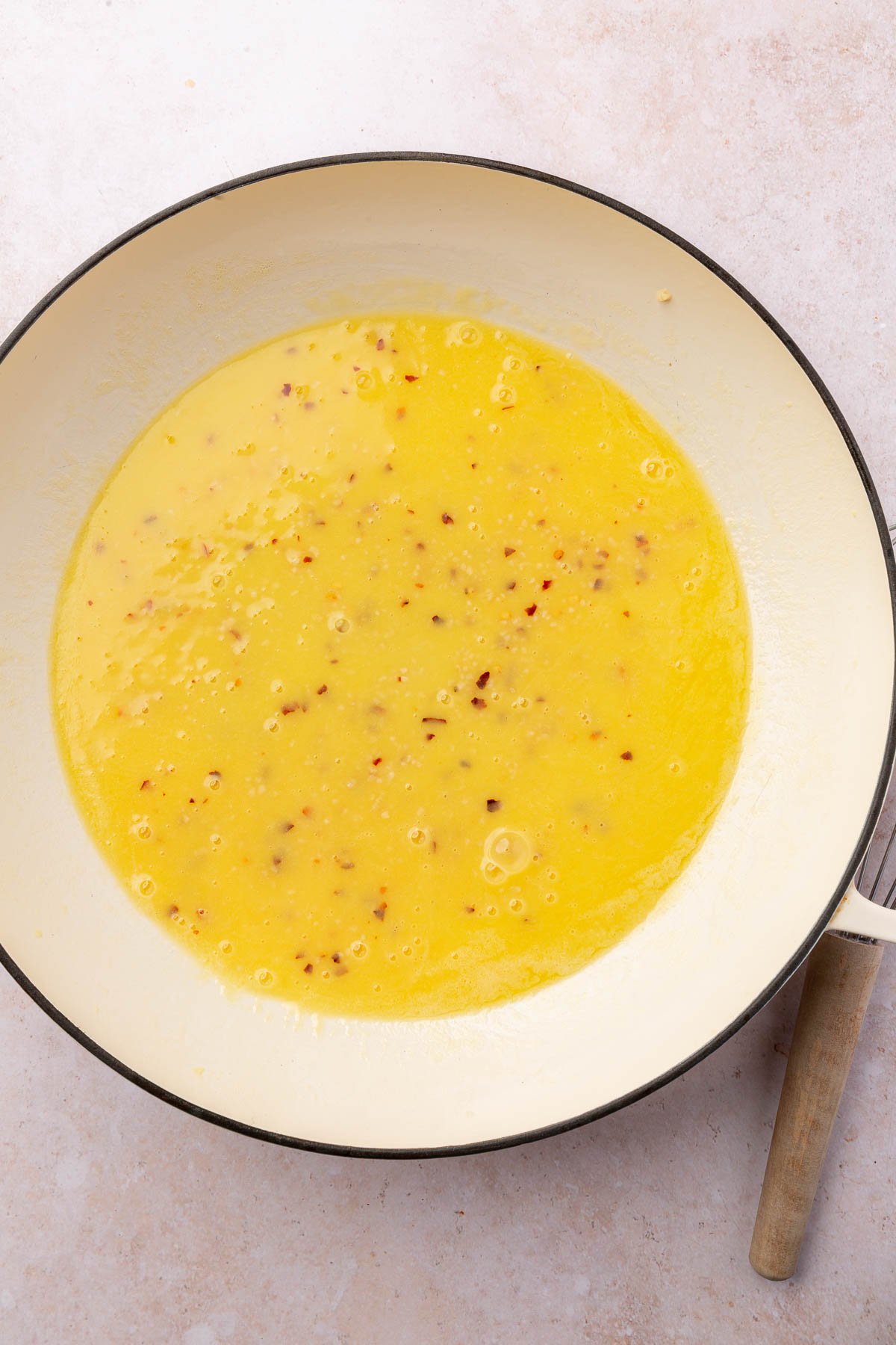 A braising pan with a butter poaching liquid with garlic and red pepper flakes.