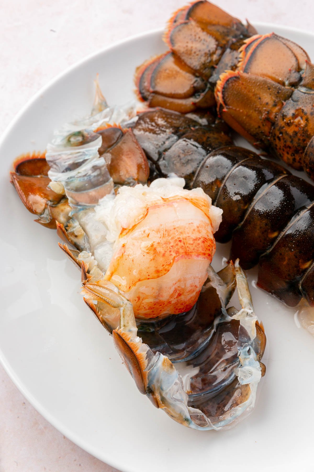 The meat of the lobster tail is partially pulled up from the shell showing the process of removing the meat from the shell before cooking.