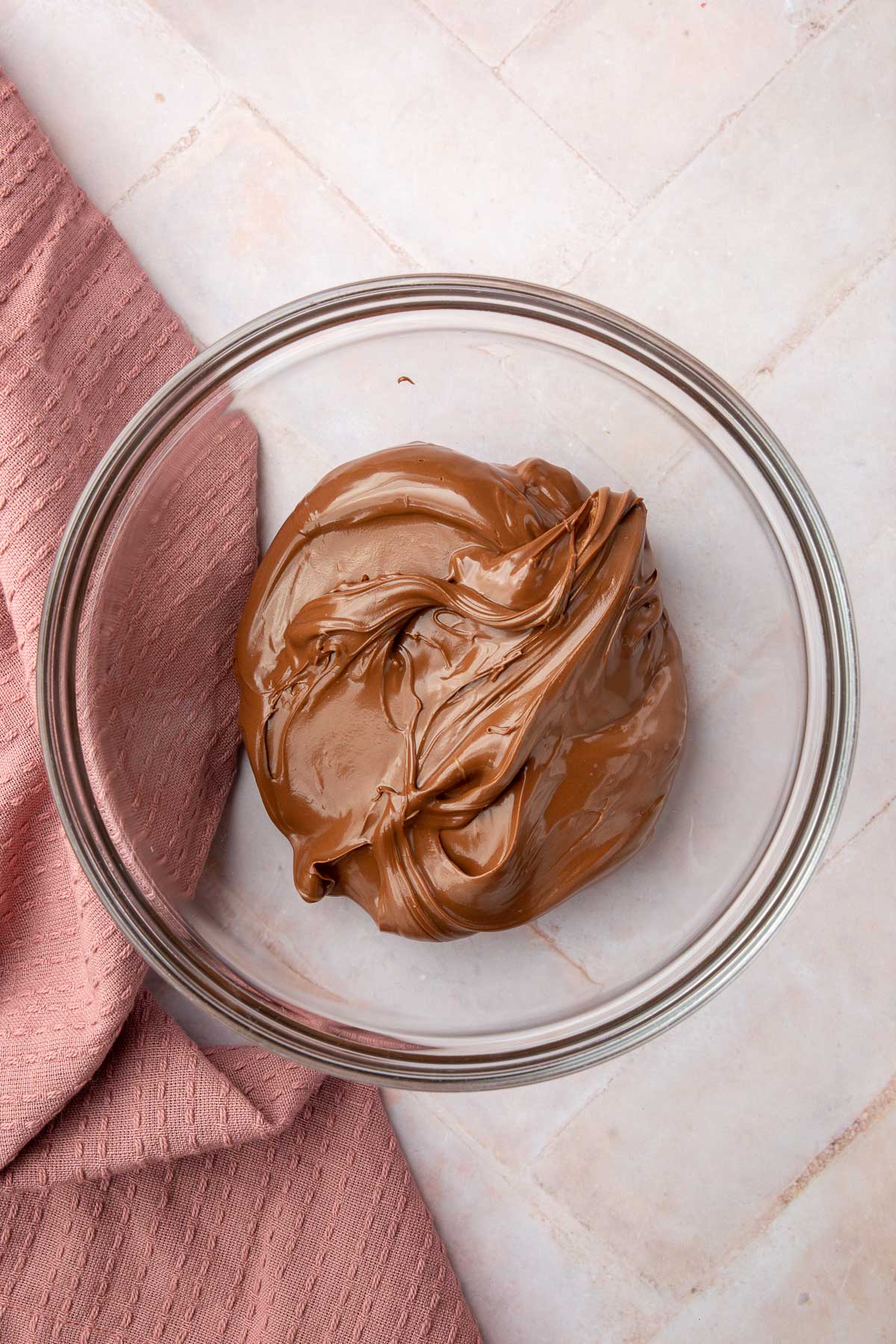 A glass mixing bowl with Nutella in it.