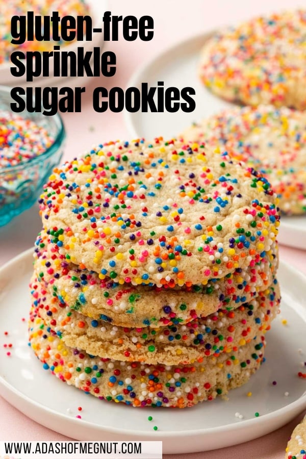 A stack of four gluten-free sprinkle sugar cookies on a dessert plate with additional cookies and sprinkles in the background.