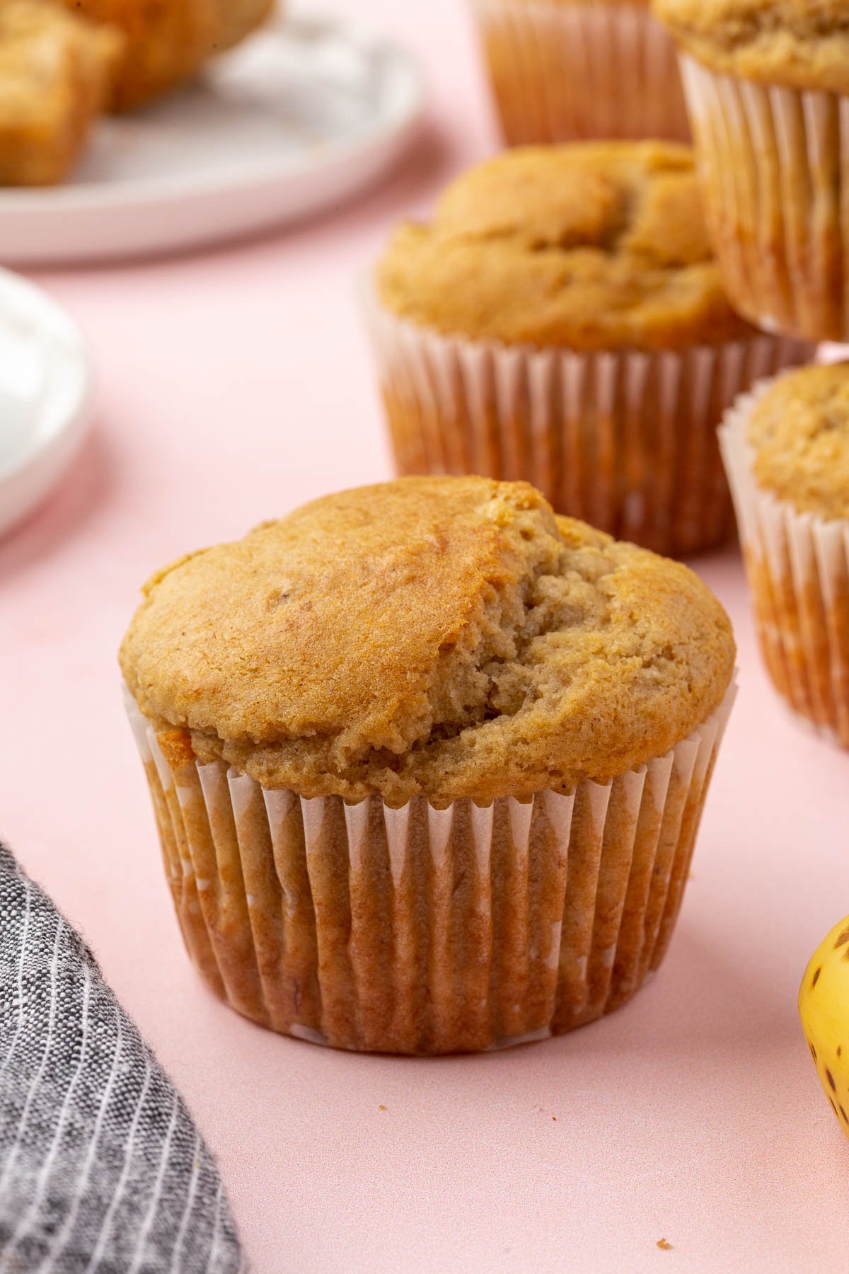 A close up of a gluten-free banana muffin with additional muffins in the background.