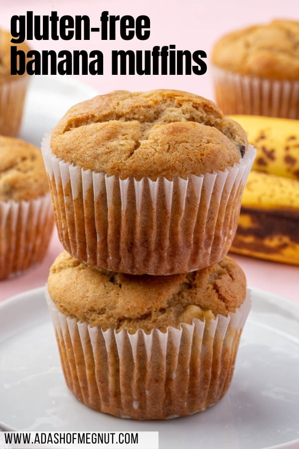 A stack of two gluten-free banana muffins on a dessert plate with additional muffins and ripe bananas in the background.
