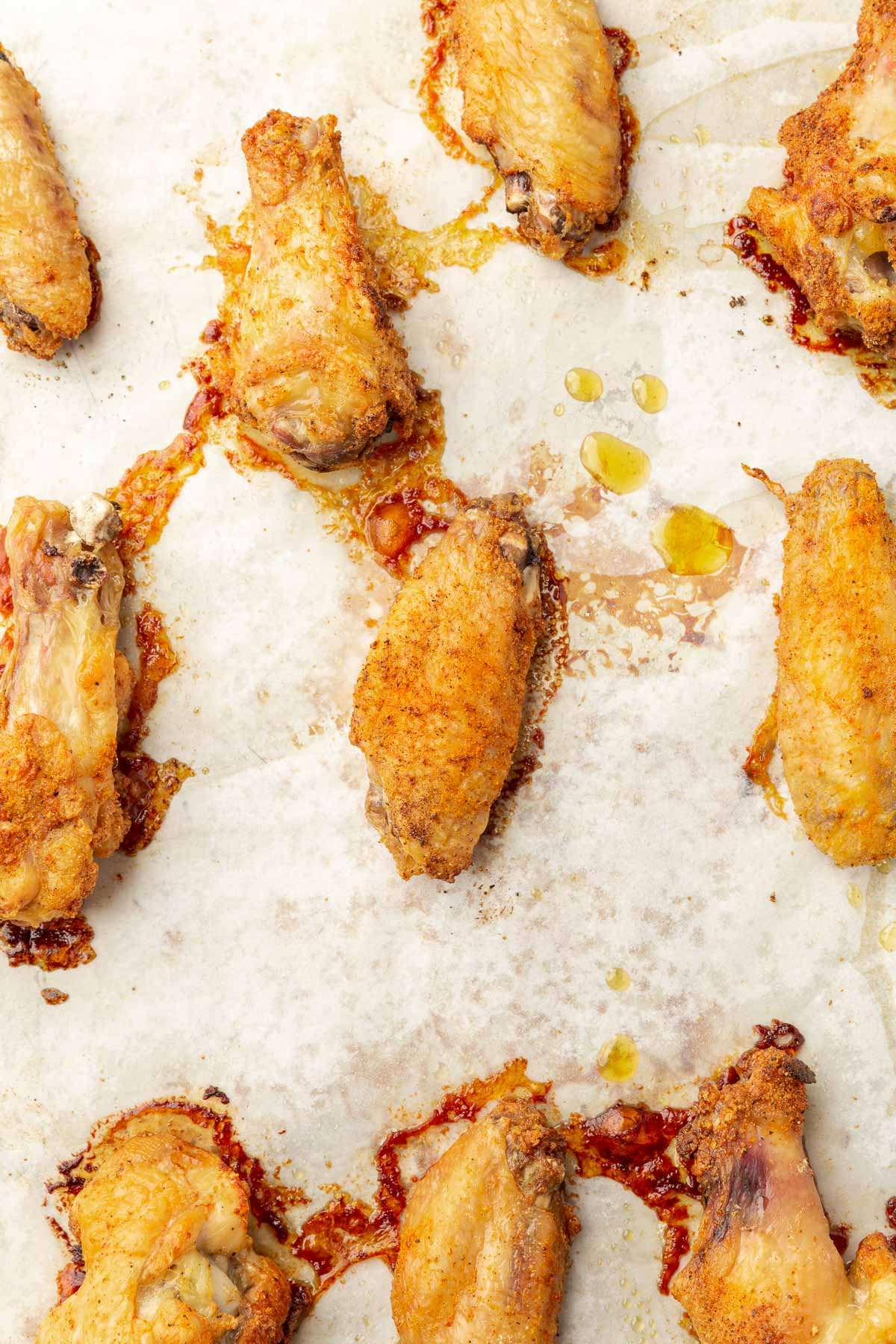 Baked chicken wings on a baking sheet lined with parchment paper.