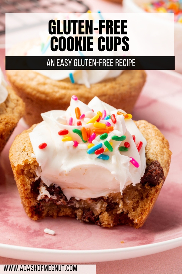 A chocolate chip cookie cup filled with vanilla frosting and topped with rainbow sprinkles that has a bite taken out of it.