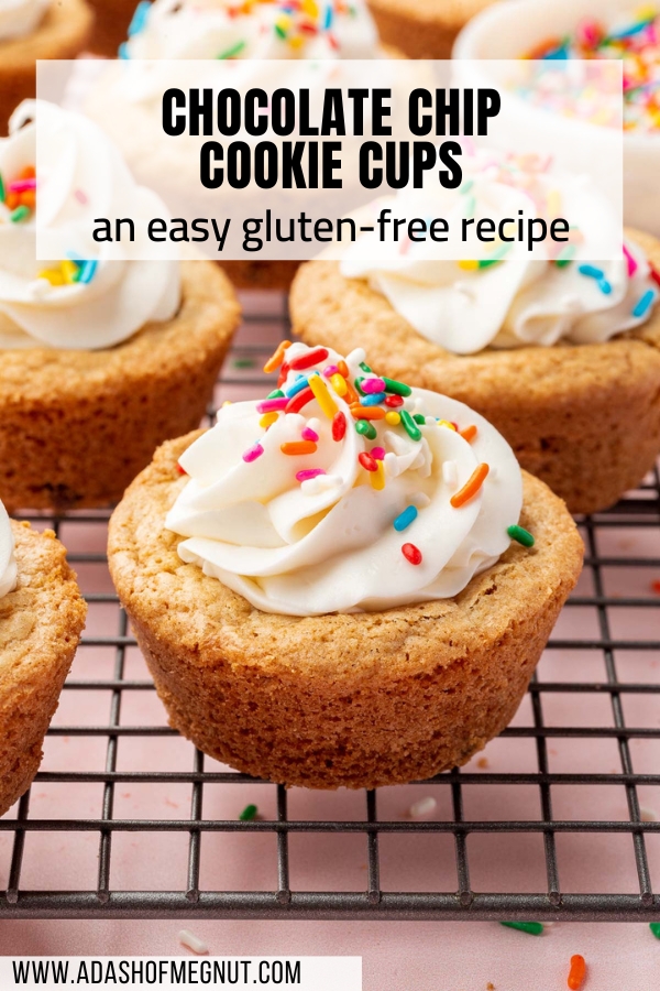 Multiple gluten-free cookie cups topped with vanilla frosting and rainbow sprinkles on a wire cooling rack.