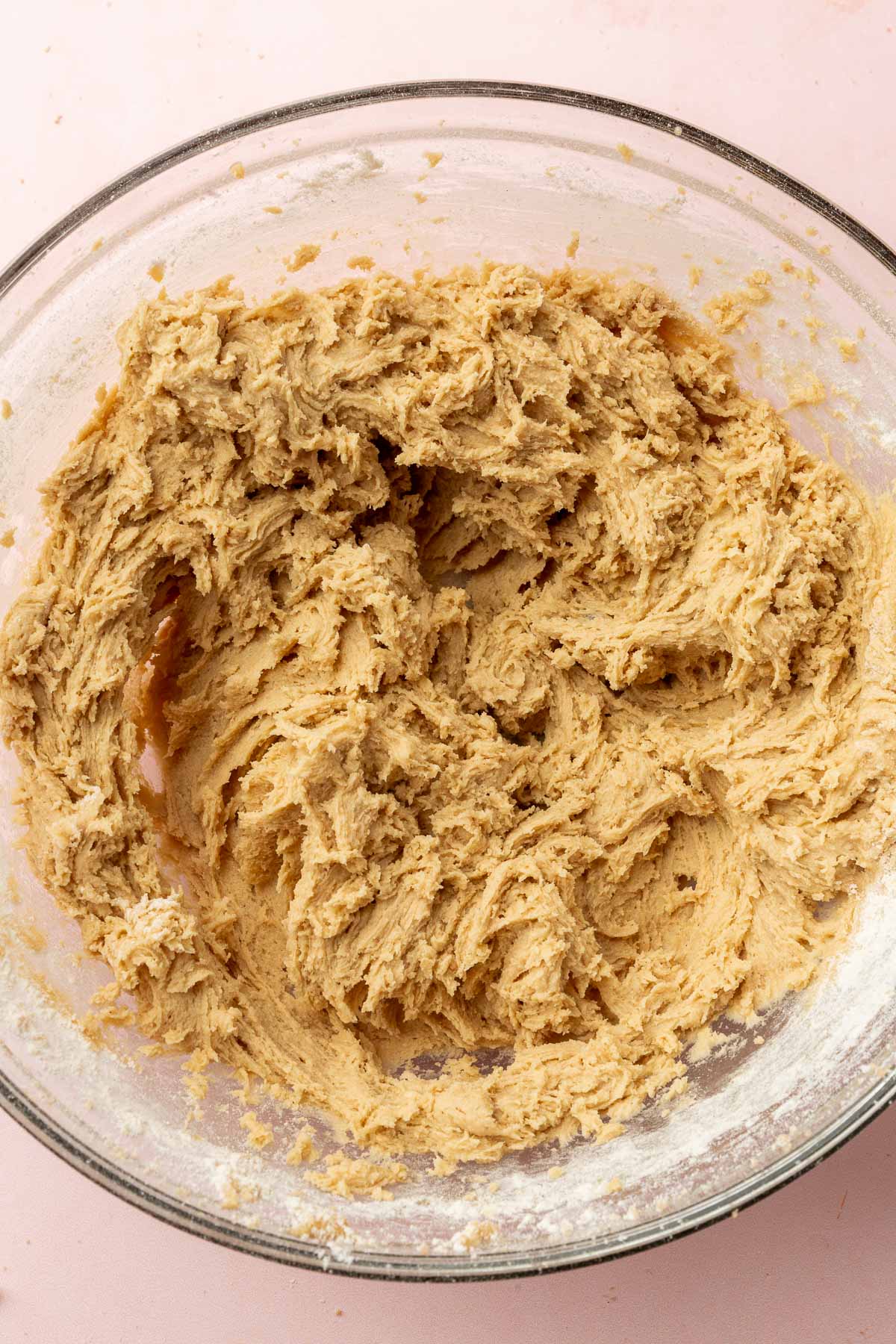 A glass mixing bowl with a gluten-free cookie dough that has been mixed together.