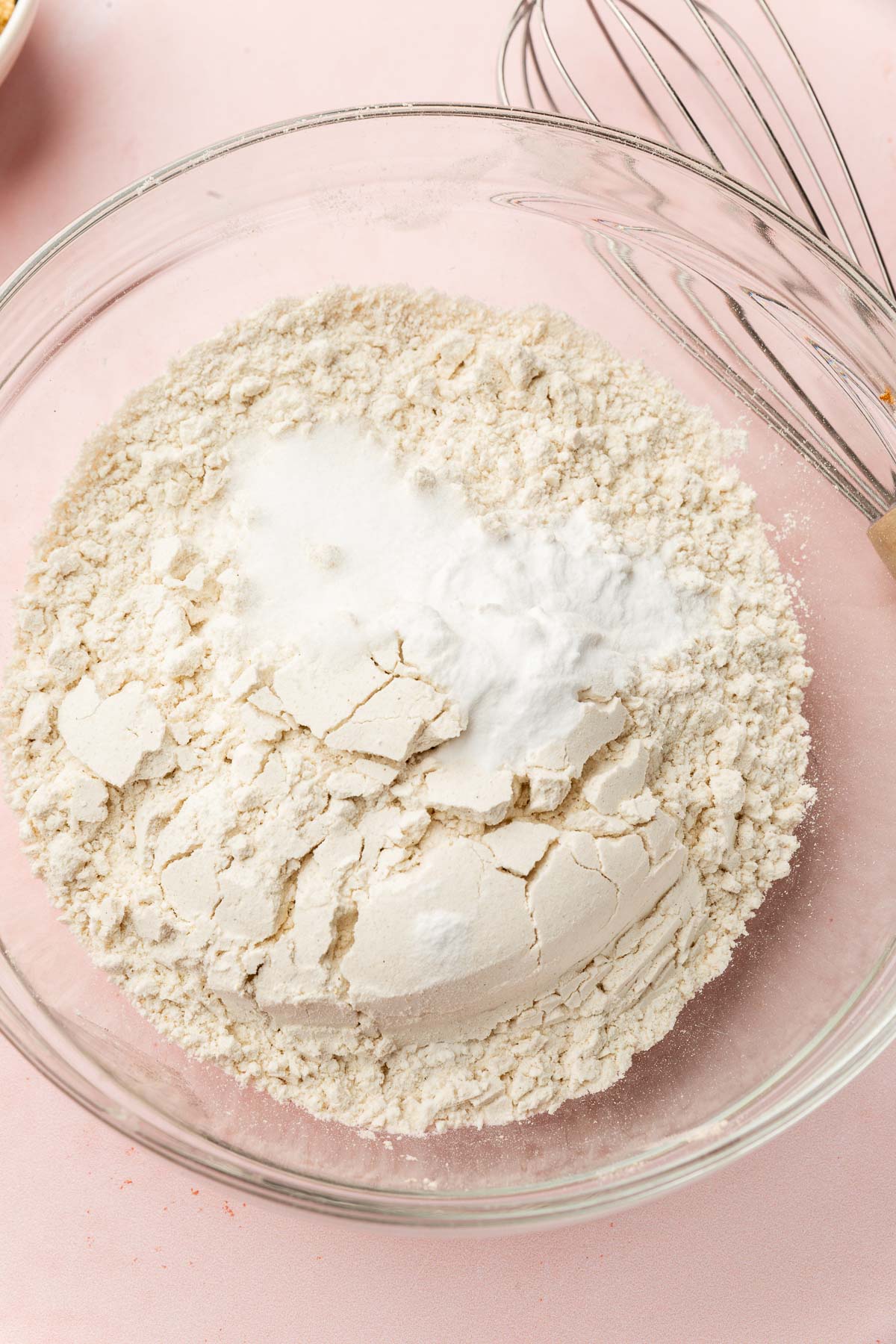 A glass mixing bowl with gluten-free flour, salt and baking soda before being whisked together.