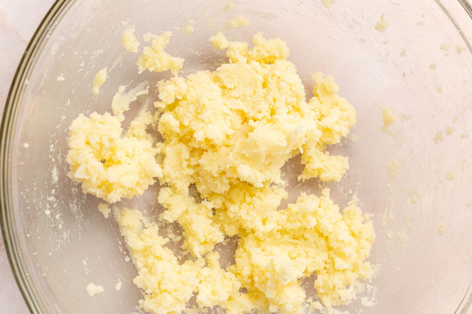 A glass mixing bowl with butter and granulated sugar creamed together.