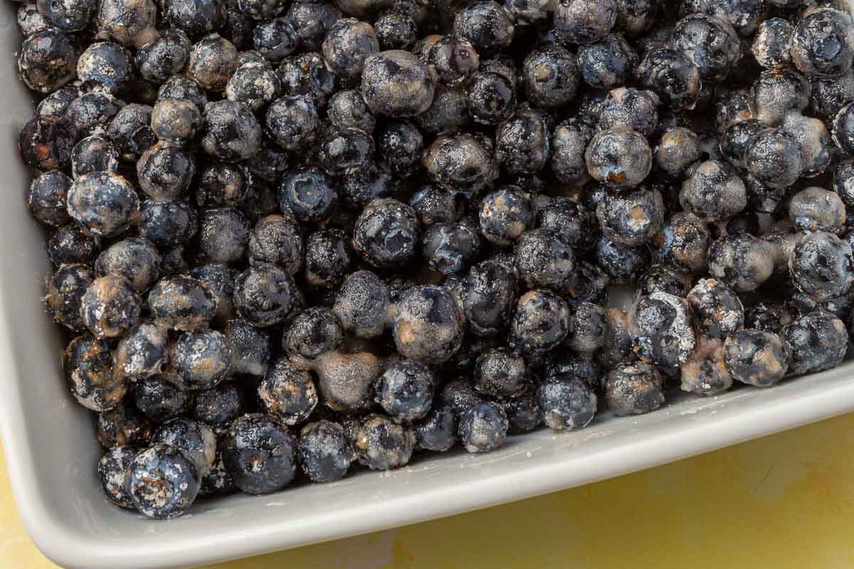 A square baking dish filled with blueberries covered in a cornstarch and lemon juice mixture.