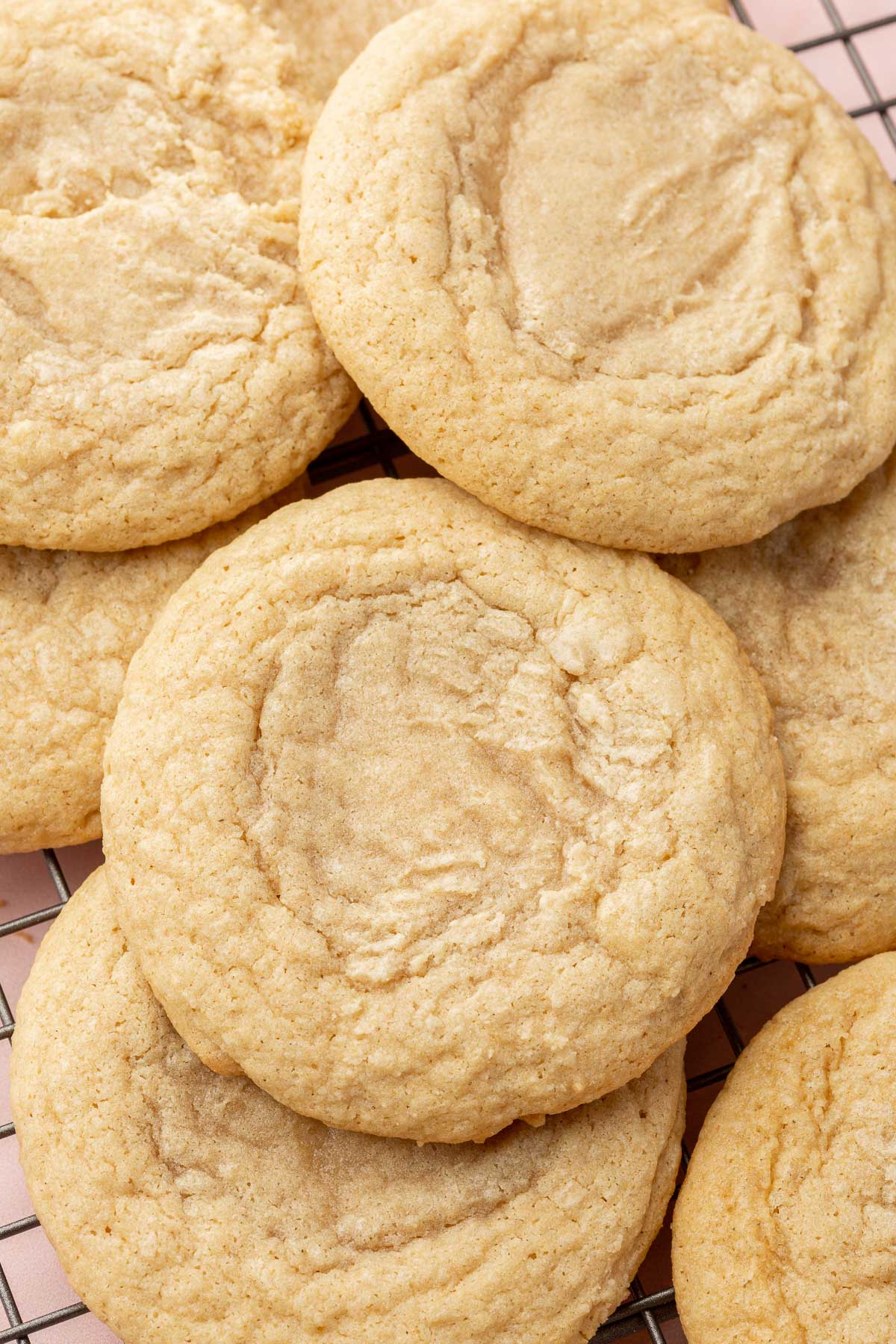 Gluten free chewy sugar cookies layered over each other on a wire cooling rack.