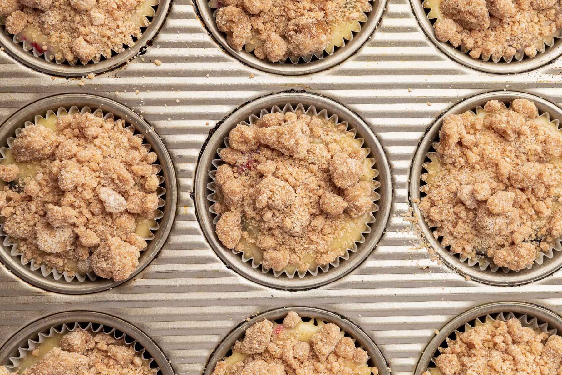 A close up of muffin wells filled with gluten-free muffin batter and topped with gluten-free streusel before baking in the oven.
