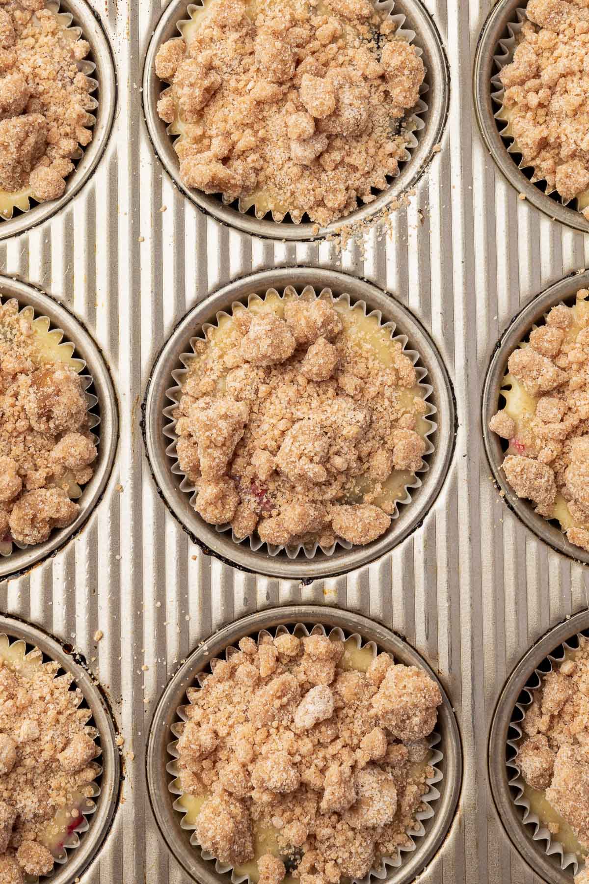 A close up of muffin wells filled with gluten-free muffin batter and topped with gluten-free streusel before baking in the oven.