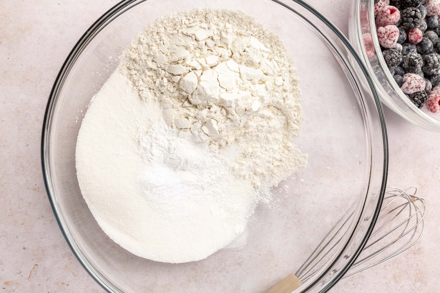 A glass mixing bowl with gluten-free flour, granulated sugar, baking soda, baking powder and salt in it before whisking together.