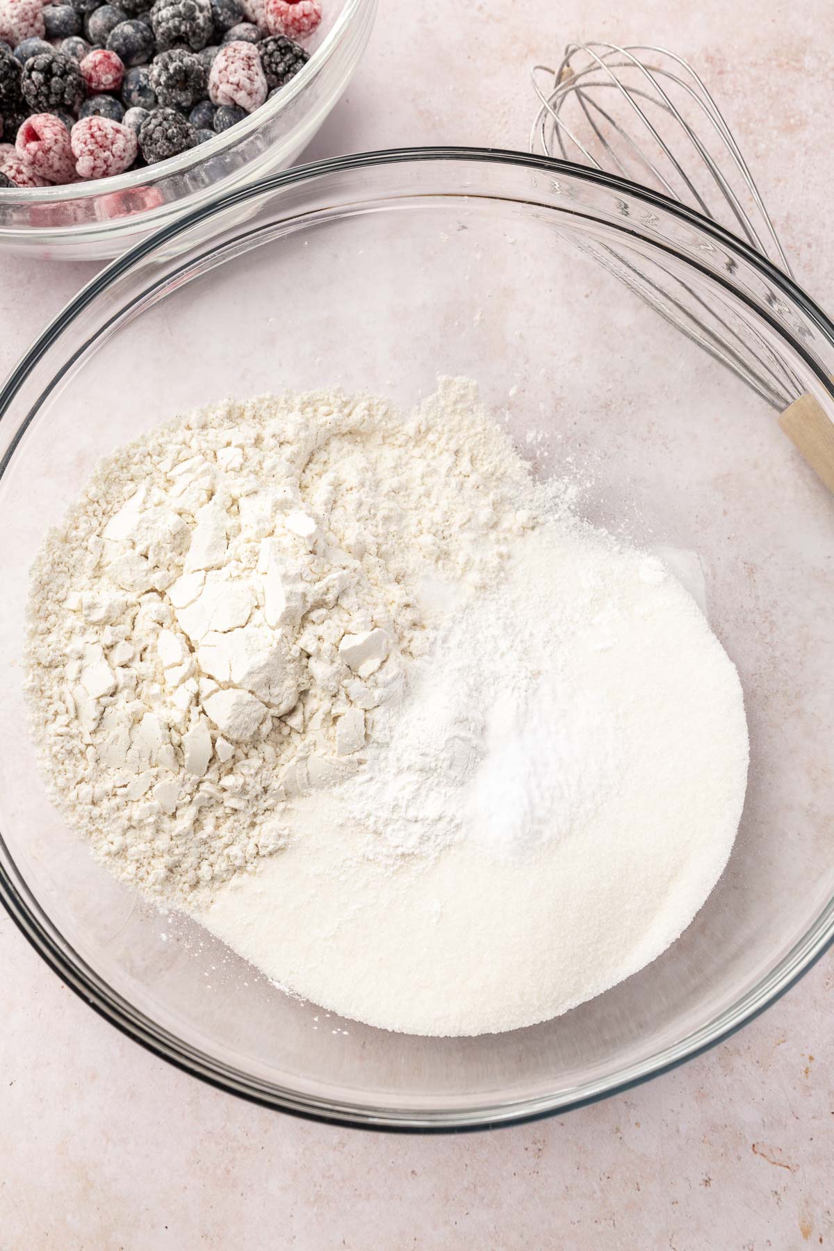 A glass mixing bowl with gluten-free flour, granulated sugar, baking soda, baking powder and salt in it before whisking together.