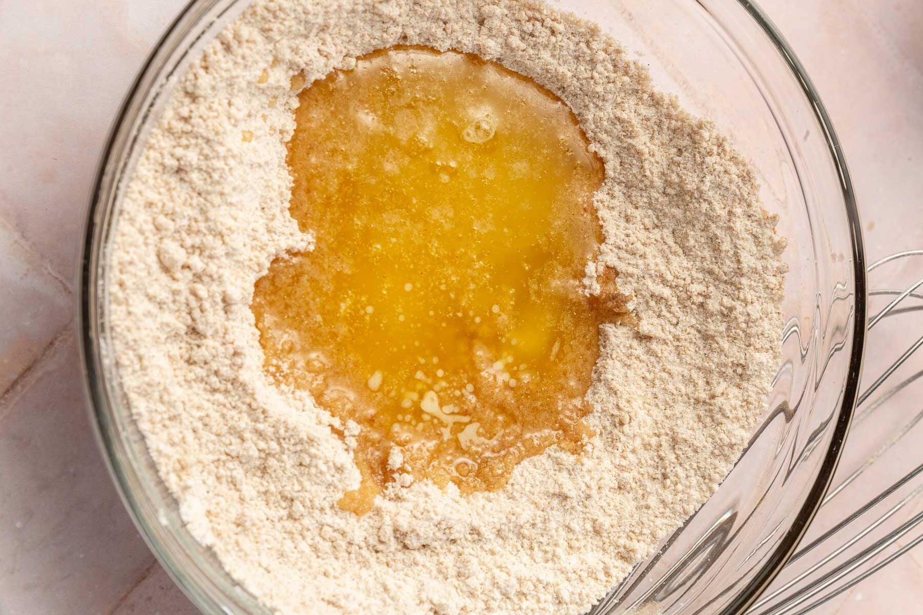 A glass bowl with flour and gluten-free melted butter pooled in the center, ready to be mixed for gluten-free streusel.