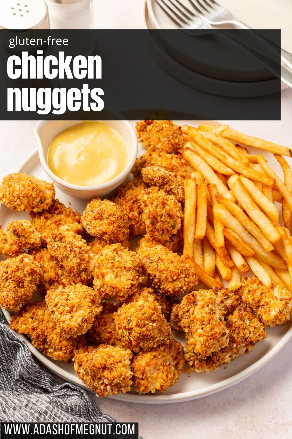 A plate of gluten-free baked chicken nuggets with french fries and a small ramekin of honey mustard.