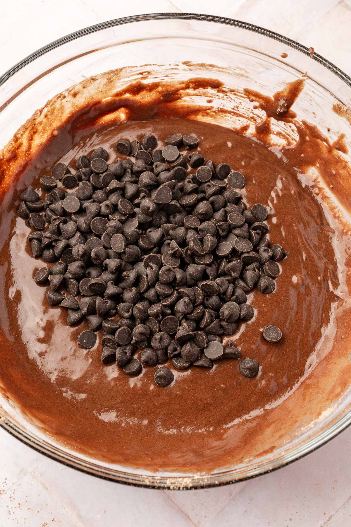A mixing bowl with chocolate chips added to the chocolate batter for gluten-free chocolate muffins, ready to be folded in.