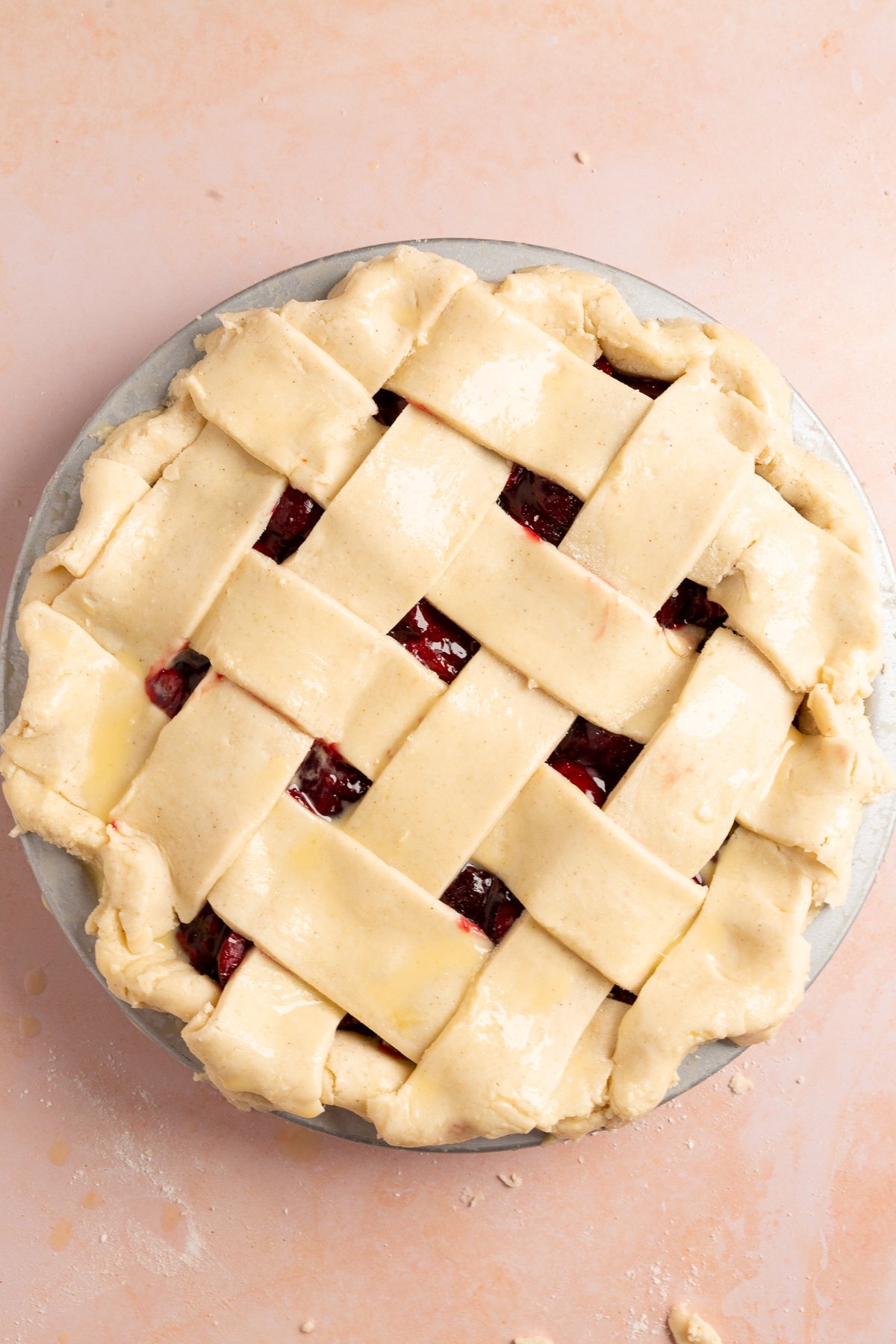 Unbaked gluten-free cherry pie with a completed lattice crust, crimped edges and brushed with egg wash, ready to bake in the oven.