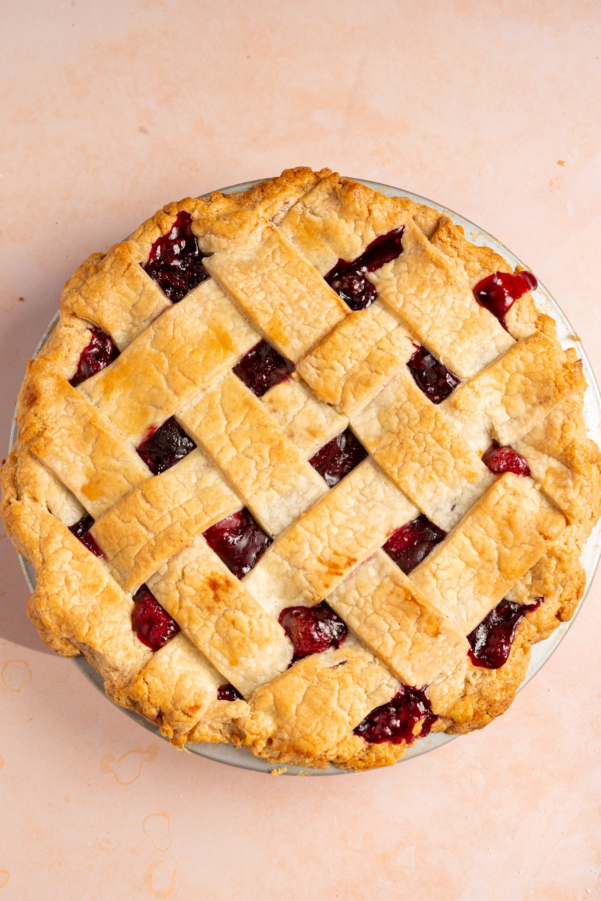 A fully baked cherry pie with a golden-brown gluten-free lattice crust, with some cherry filling bubbling through the lattice openings.