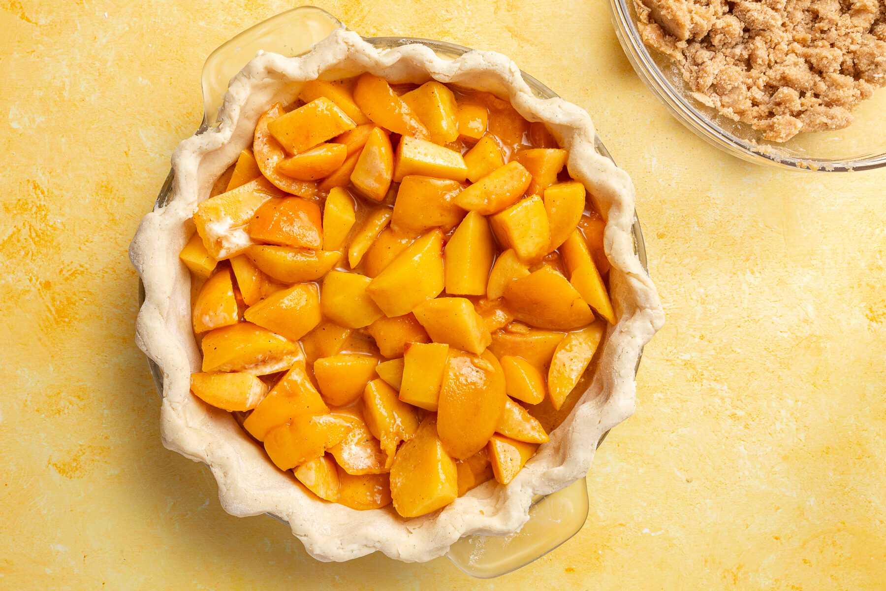 Peach filling mixture poured into the unbaked gluten-free pie crust, filling the pie dish.