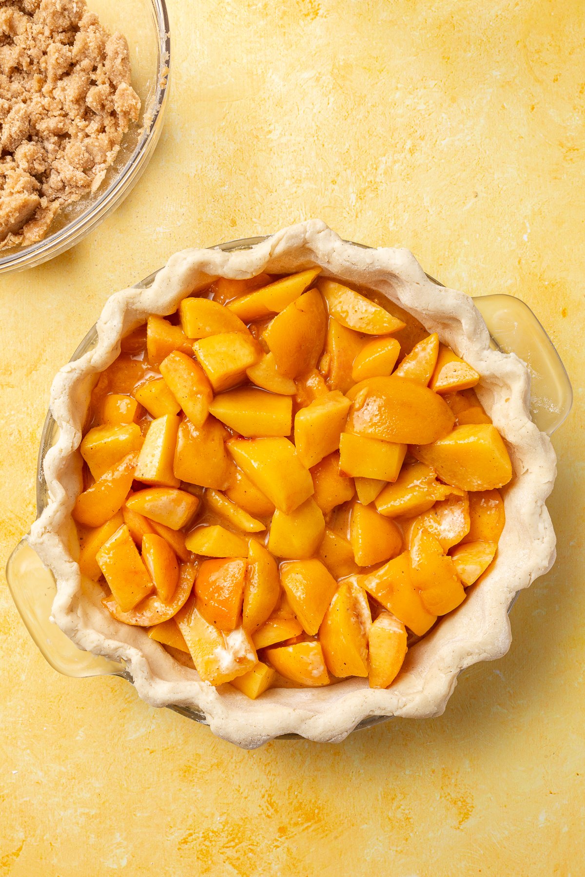 Peach filling mixture poured into the unbaked gluten-free pie crust, filling the pie dish.