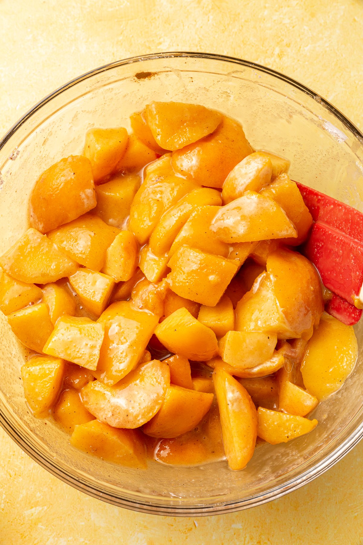 Peach filling mixture with sugar and spices fully combined in a bowl, showing the peaches coated in the mixture.